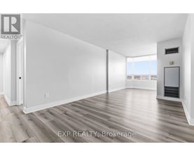 A spacious room with wood flooring and white walls.
