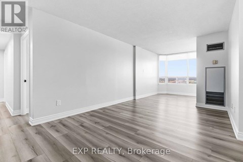 A spacious room with wood flooring and white walls.