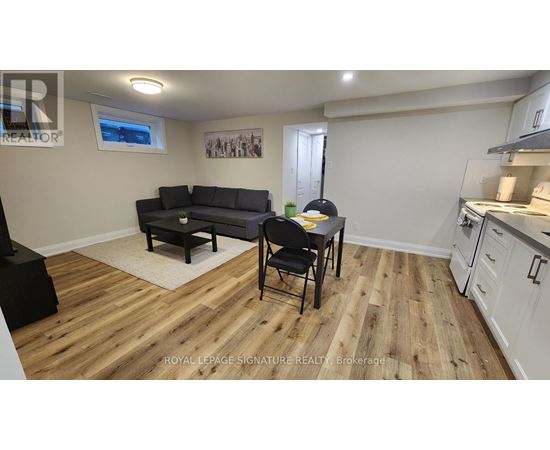 A living room with a black couch and a wooden floor.