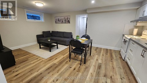 A living room with a black couch and a wooden floor.