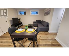 A dining room with a table set for two and a couch in the background.