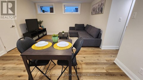 A dining room with a table set for two and a couch in the background.