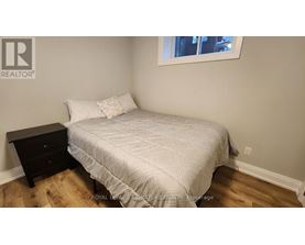 A bedroom with a bed, nightstand, and window.