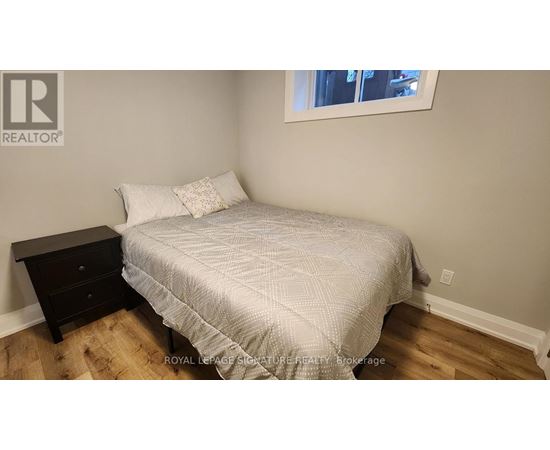 A bedroom with a bed, nightstand, and window.