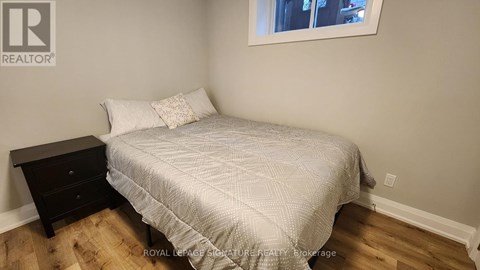 A bedroom with a bed, nightstand, and window.