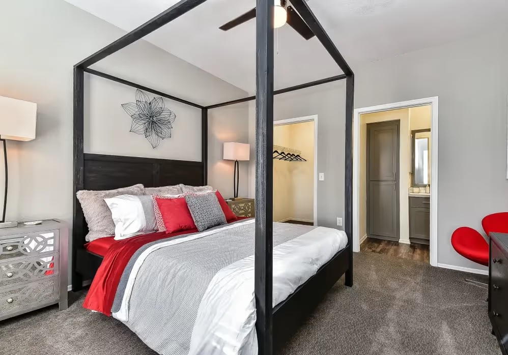 A bedroom with a four poster bed and a chair.