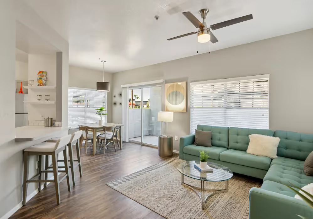 A living room with a green couch and a glass table.