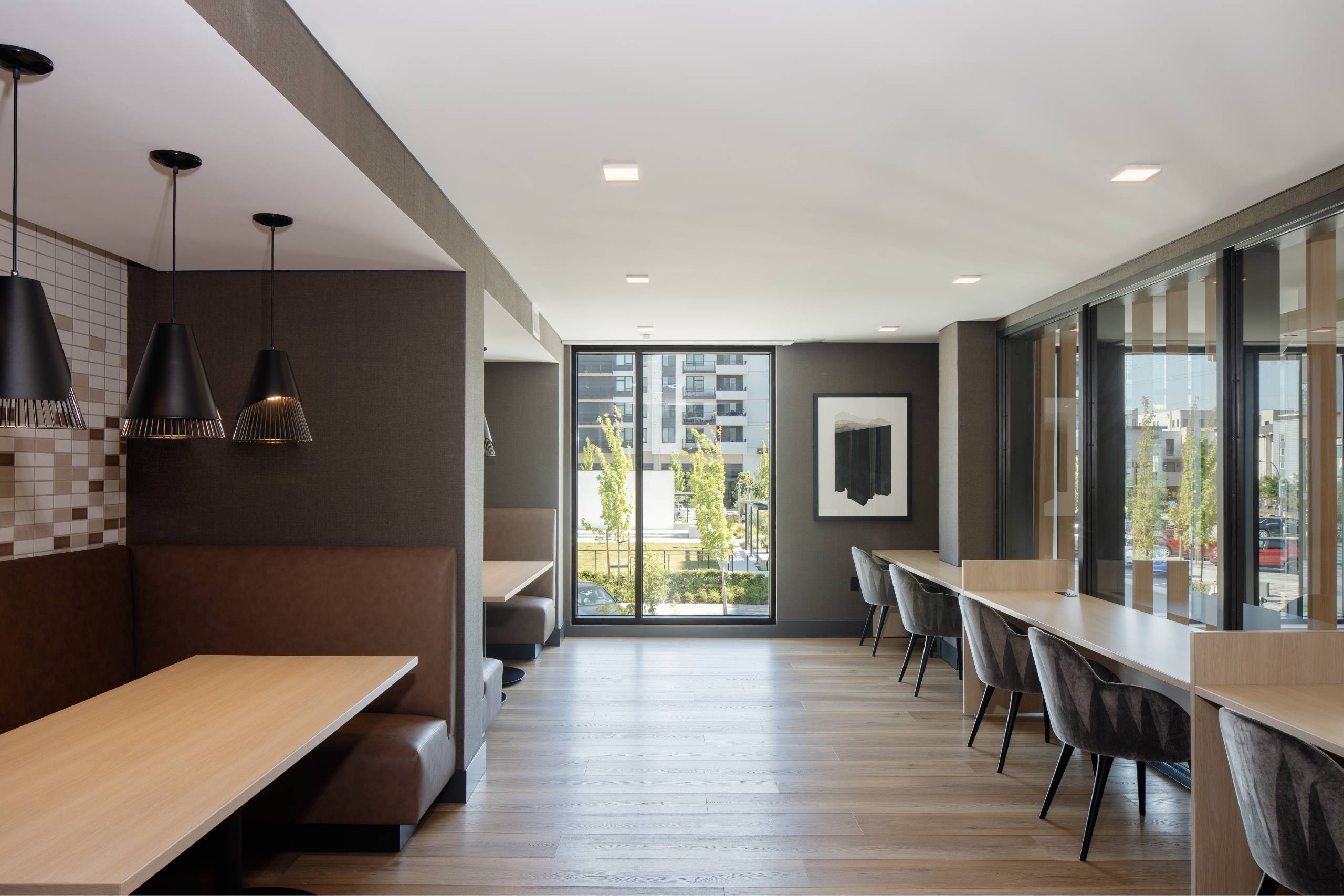 A long, narrow dining room with wooden tables and chairs.
