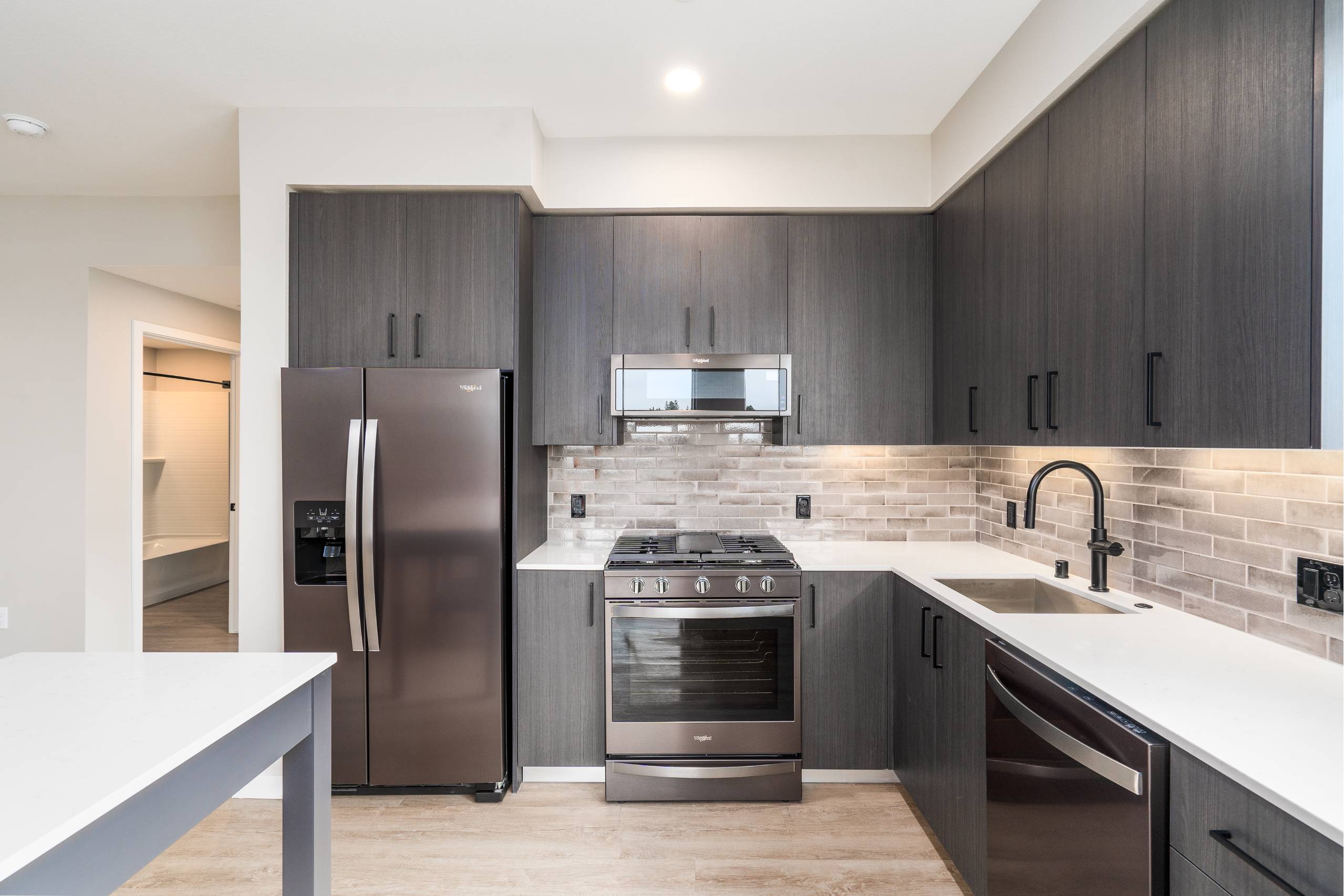 A modern kitchen with dark wood cabinets and stainless steel appliances.