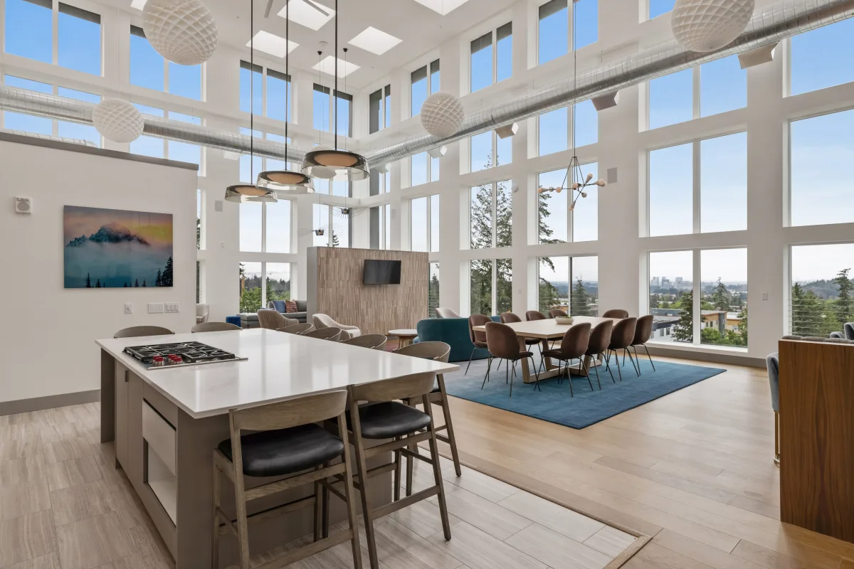 Resident lounge with tables, chairs, and floor-to-ceiling windows at Nightingale Apartments in Redmond, WA.