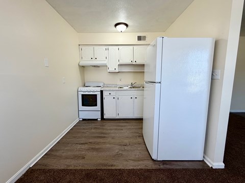 A kitchen with white appliances and cabinets.