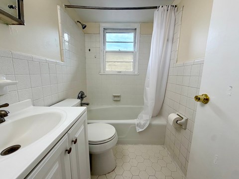 A white bathroom with a toilet, sink, and tub.