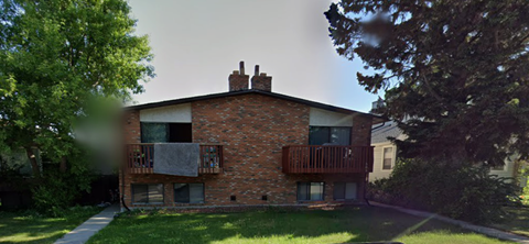 A brick house with a balcony and a chimney.