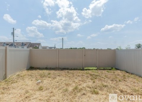 A backyard with a fence and a grassy area.