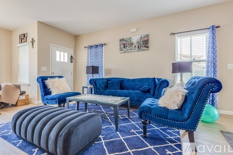 A living room with blue furniture and a white rug.