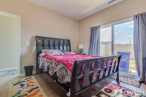 A bedroom with a large bed and a view of the outside through a window.