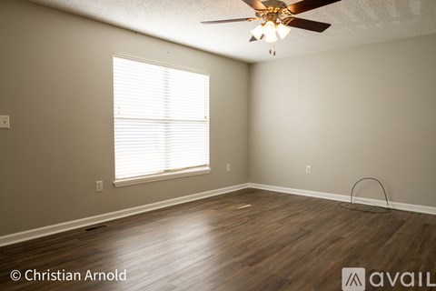 A room with a ceiling fan and a window with blinds.