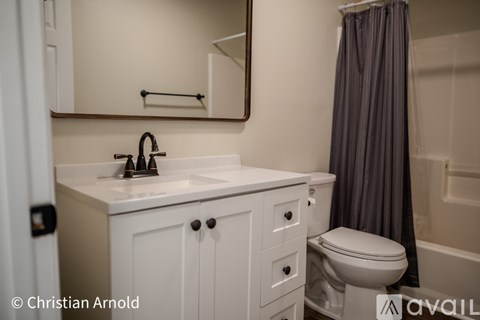 A white bathroom with a sink, toilet, and a shower curtain.