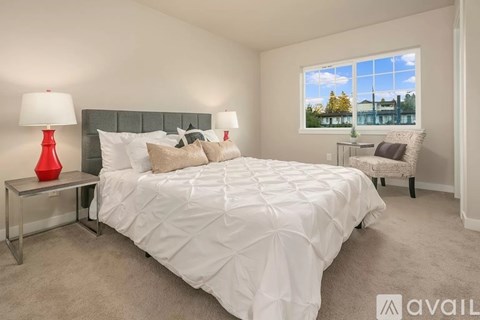 A bedroom with a large bed and a window showing a view of a building and trees.
