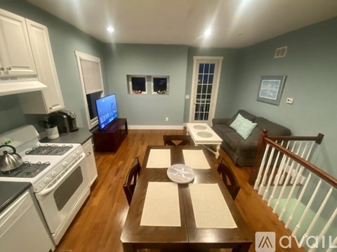 A kitchen with a stove top oven and a dining table with chairs.