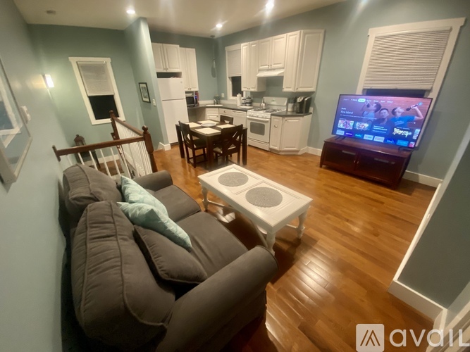 A living room with a grey couch and a television on a stand.