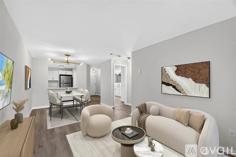 A modern living room with a large couch, a coffee table, and a painting on the wall.