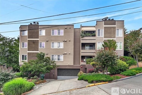 A modern apartment building with a garage door and a balcony on the second floor.