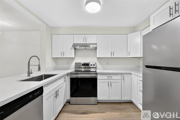 A modern kitchen with white cabinets and stainless steel appliances.
