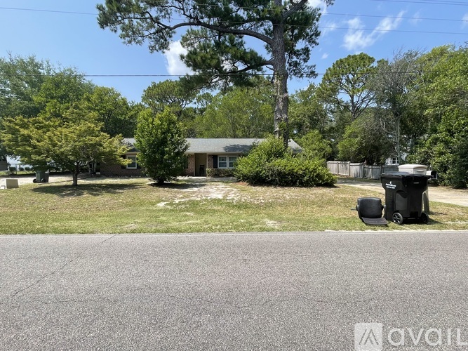 A residential area with a house, trees, and a trash can.