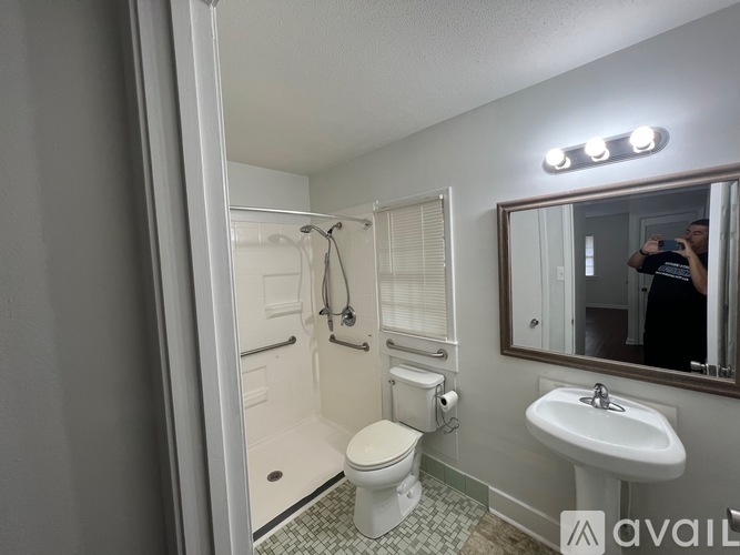 A bathroom with a toilet, sink, and mirror.