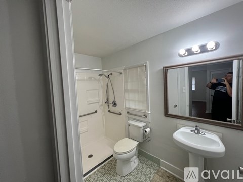 A bathroom with a toilet, sink, and mirror.