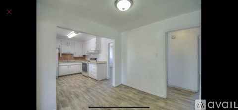 A kitchen with white cabinets and a wooden floor.