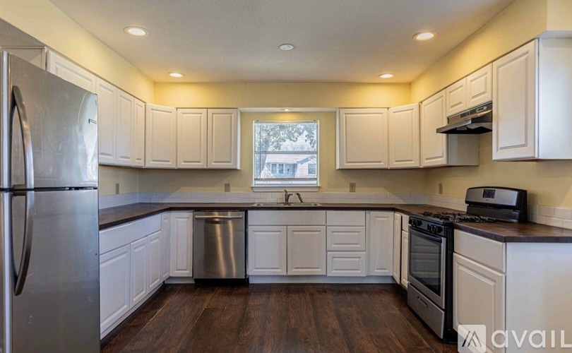 A kitchen with white cabinets and a stainless steel refrigerator.
