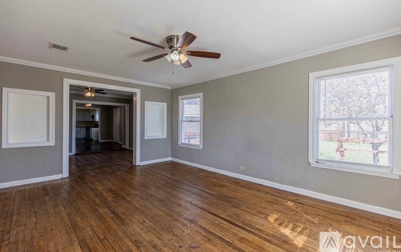 A room with a ceiling fan and wooden flooring.