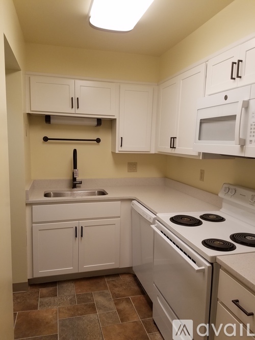 A kitchen with white cabinets and a white stove top oven.