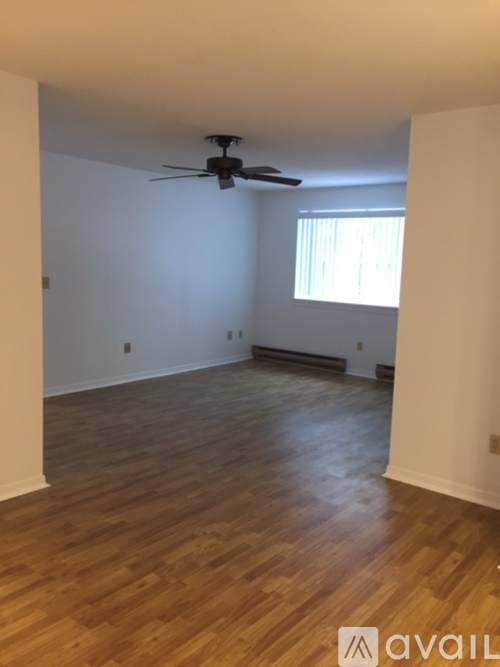 A room with a ceiling fan and wooden flooring.