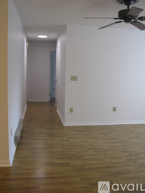 A long hallway with a fan and wood floors.