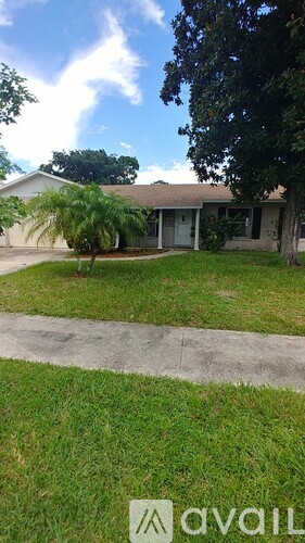 A house with a lawn and a tree in front of it.