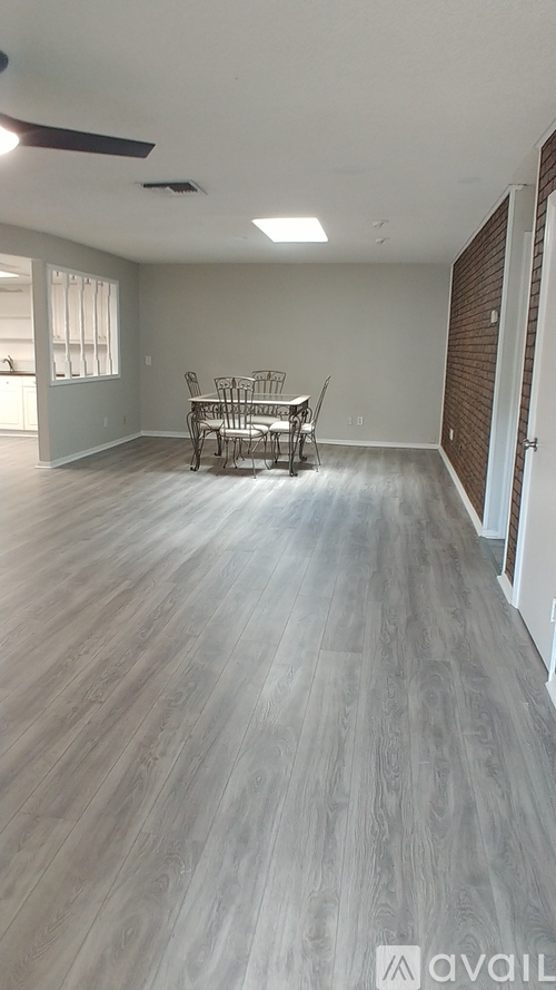 A room with wooden flooring and a table with chairs.