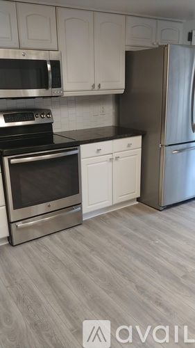 A kitchen with a stainless steel refrigerator, microwave, oven, and cabinets.