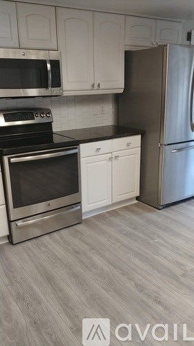 A kitchen with a stainless steel refrigerator, microwave, oven, and cabinets.