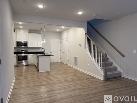 A spacious kitchen with a stainless steel oven and microwave, a dining table with chairs, and a staircase with a railing.