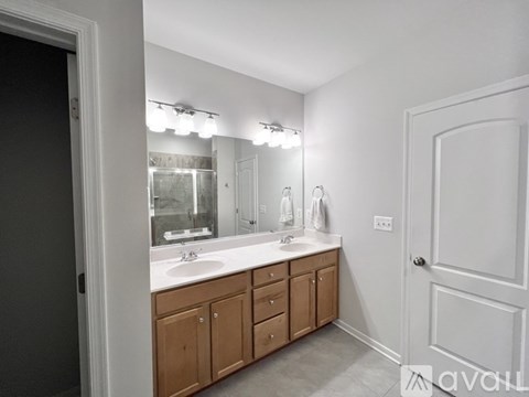 A bathroom with a vanity, sink, mirror, and lights.