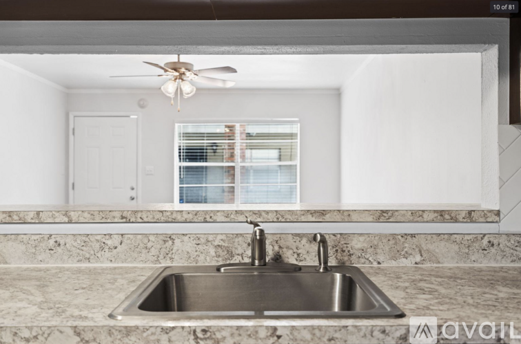 A kitchen with a marble countertop and a stainless steel sink.