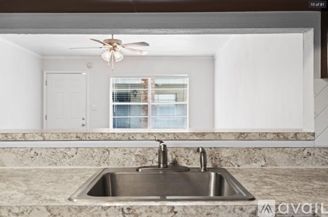 A kitchen with a marble countertop and a stainless steel sink.