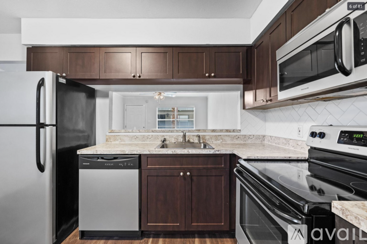 A kitchen with a black fridge, black oven, and brown cabinets.