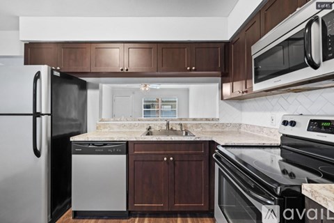 A kitchen with a black fridge, black oven, and brown cabinets.