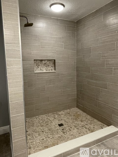 A shower area with a tiled wall and floor.