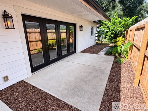 A white house with a brown gravel pathway leading to a set of black double doors.