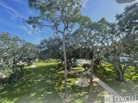 A tree in a grassy area with a house in the background.